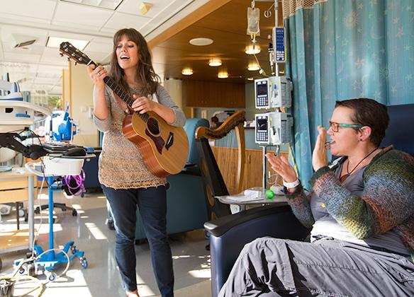 An SPU student plays the guitar for a hospital patient